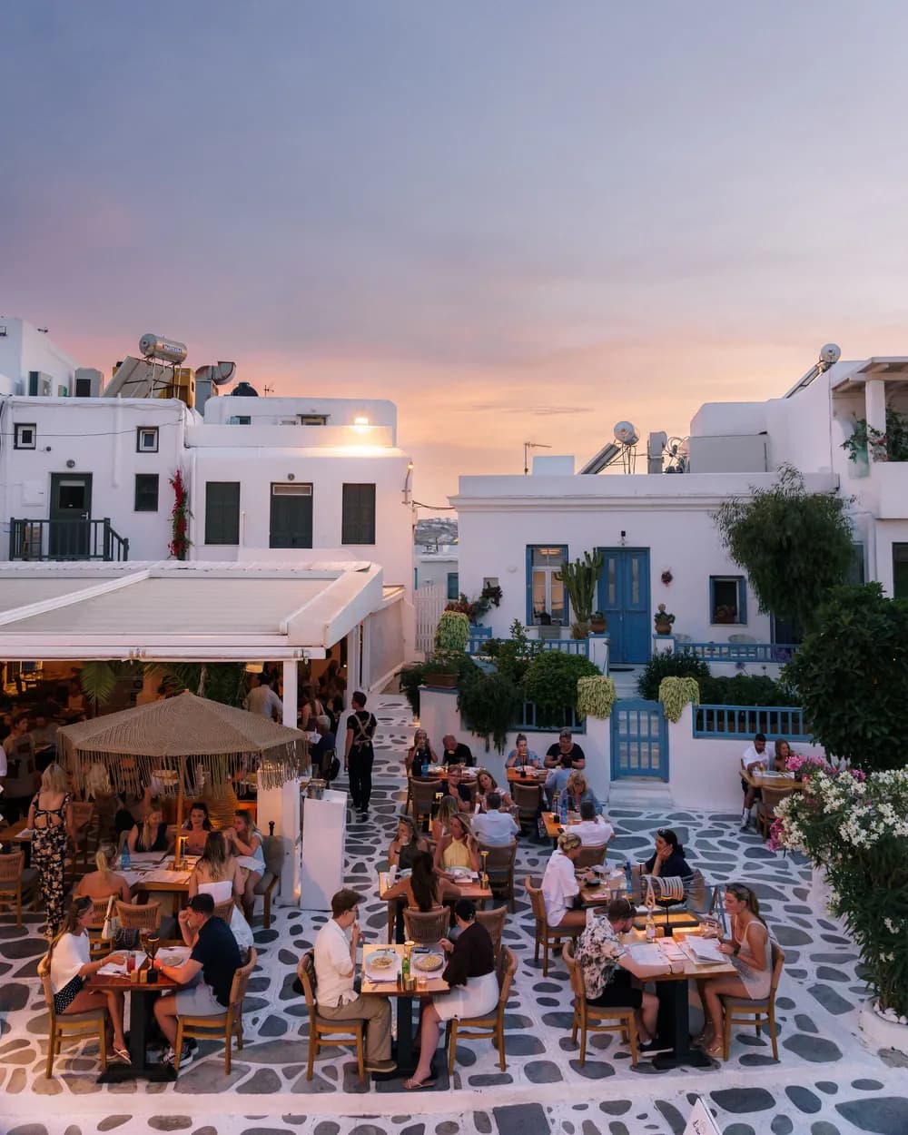 d'angelo restaurant terrace at sunset with guests dining amid whitewashed Cycladic buildings