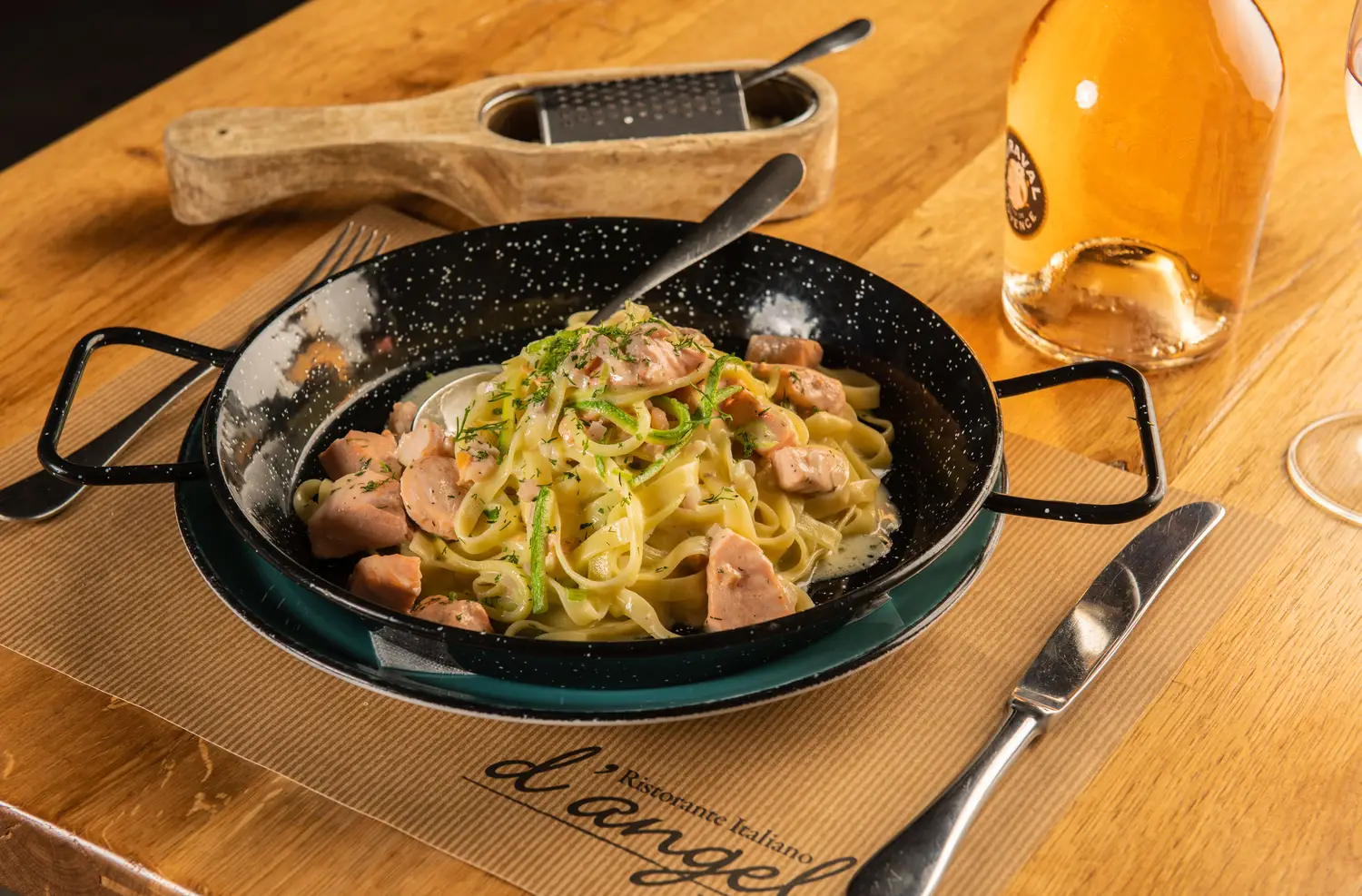 Outdoor dining area at d'angelo restaurant in Mykonos with whitewashed walls, wooden tables, and Cycladic architecture