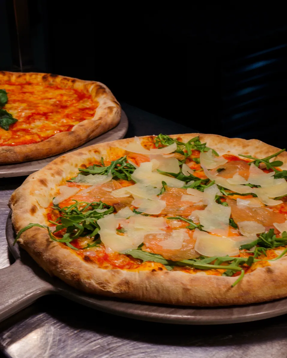 Wood-fired pizzas with prosciutto, arugula, and shaved parmesan